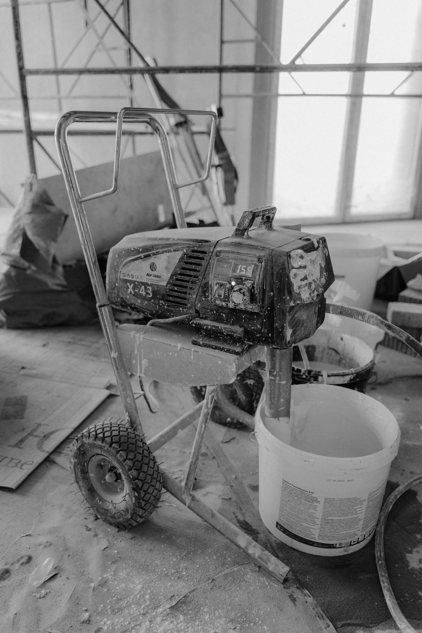 Black and white image of a paint machine on a dusty construction site.